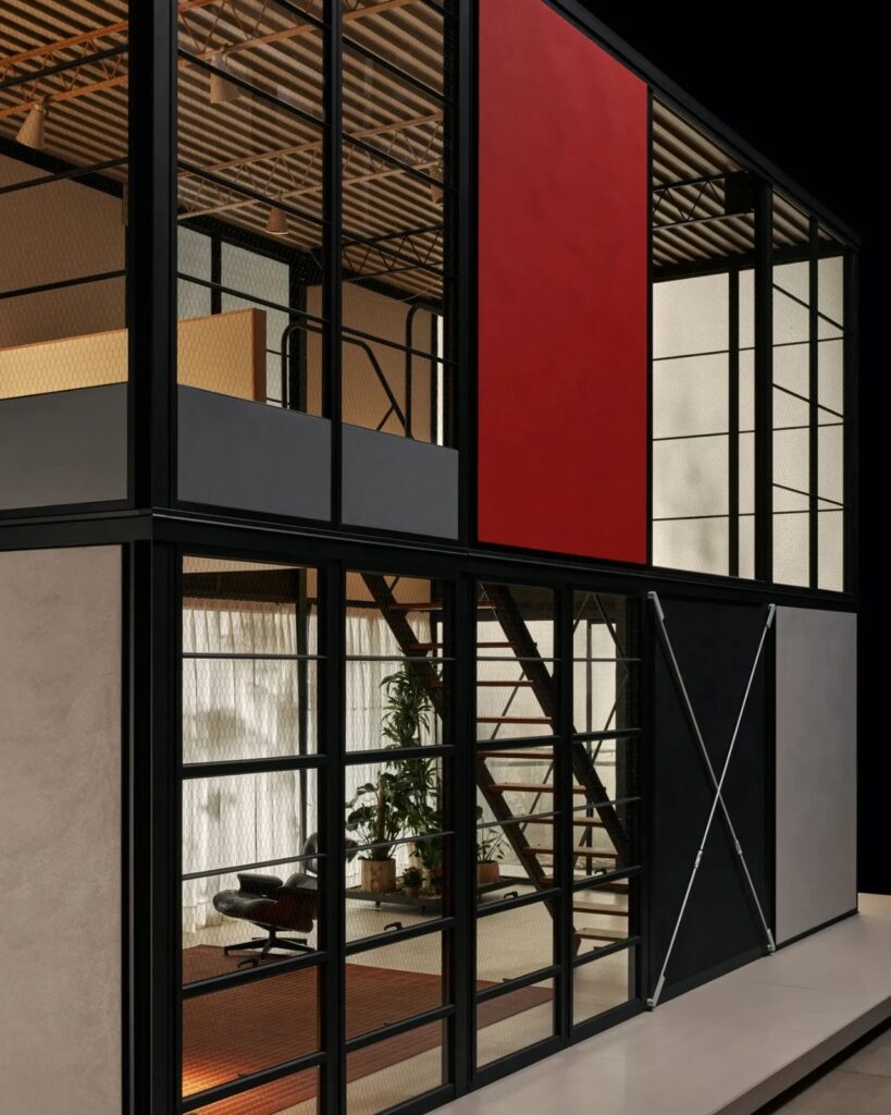 Perspective view of the Eames Pavilion System showing the red exterior panel and internal staircase through glass.