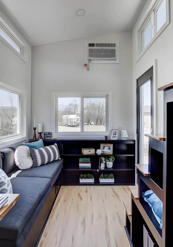 Interior view of the Espresso tiny house living room featuring a large window and matte black shelving units.