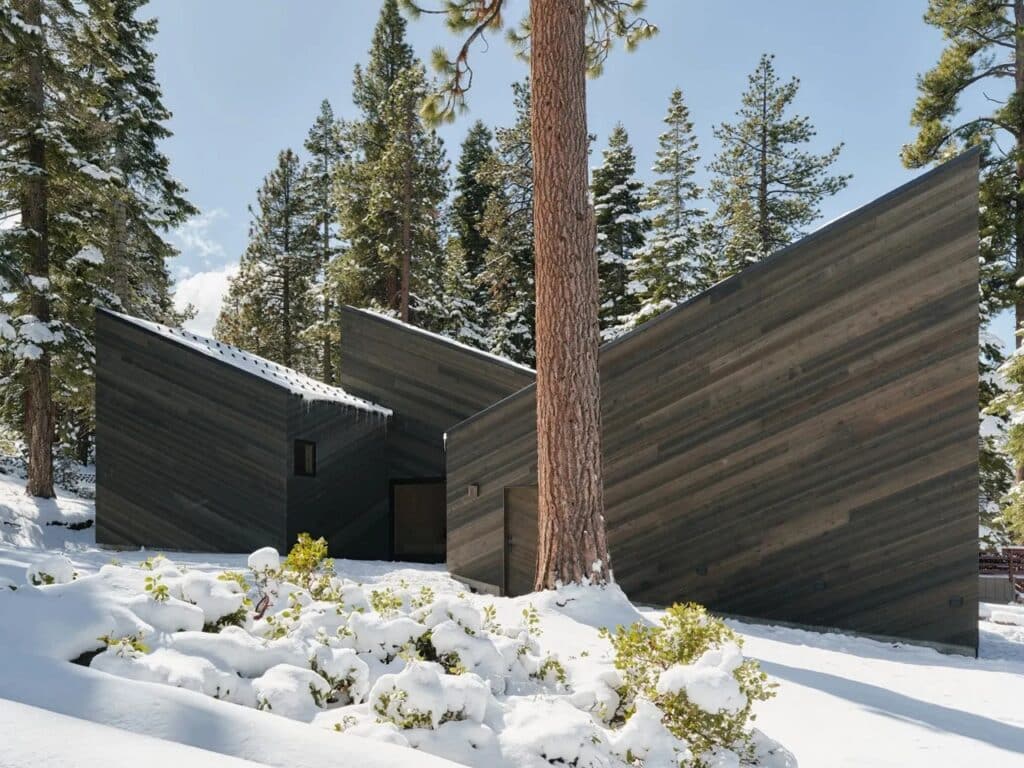 Detailed view of the intermediate outdoor spaces and dark cedar cladding of the Staggered Cabin.