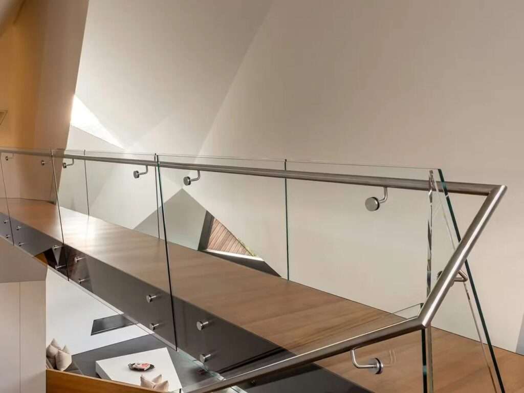 Close-up of the glass and steel railing of a bridge-like walkway inside Hadaway House.