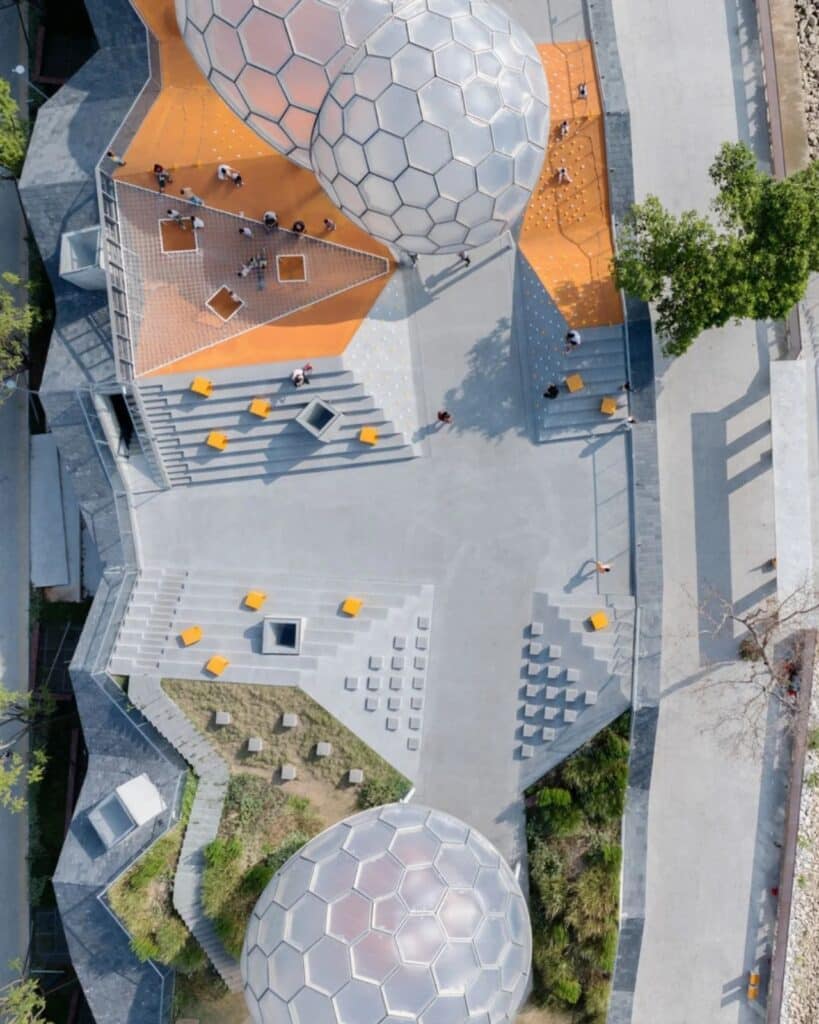 Top-down aerial view of the geometric rooftop playground at Yongping Warehouse with orange play surfaces and gray stairs.