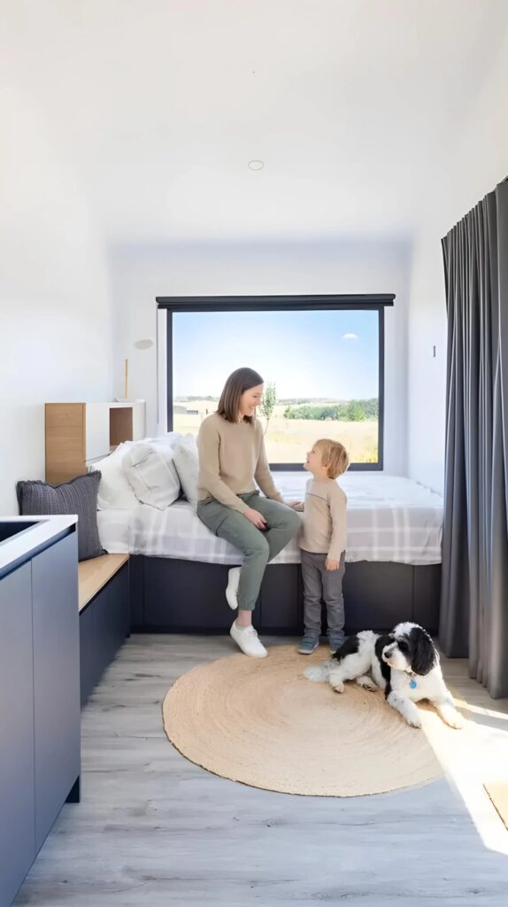 Interior of Audrey tiny home showing a family in the bedroom area with a large picture window.