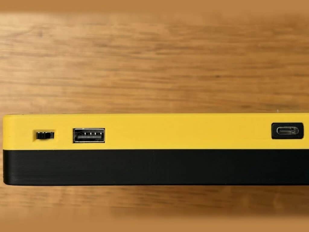 Side profile of the Bee Write Back device showing the USB ports and the power switch on the yellow and black frame.