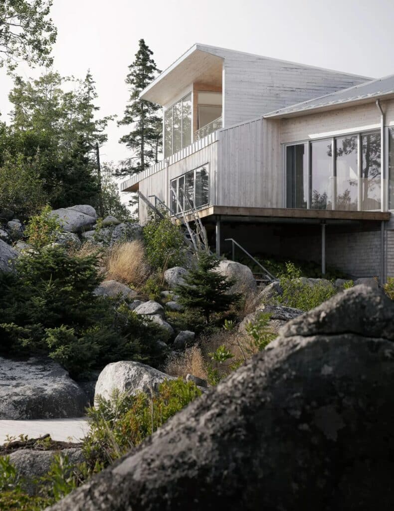 Architectural detail of East River Residence yoga studio wing rising above the rocky cliffs with a wooden deck.