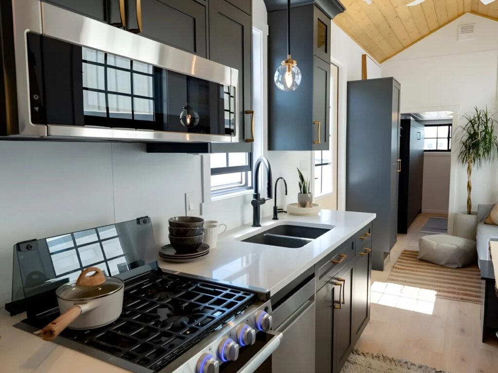 Modern kitchen appliances in Harmony tiny home including a gas stove and stainless steel microwave.