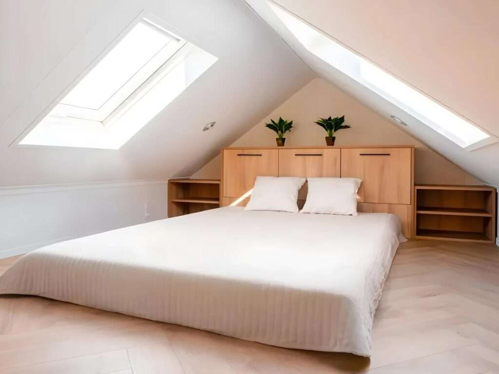 Loft bedroom in Lox tiny home with a white mattress and dual skylights on a sloped ceiling.