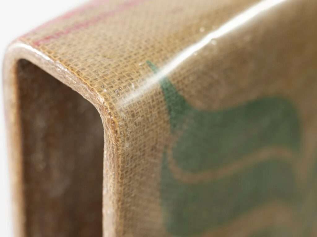 Detail of the curved edge of the Novum Chair highlighting the seamless integration of natural fabric and bio-resin.