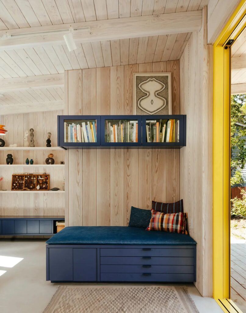 Built-in blue daybed with storage drawers and overhead bookshelves in a modern studio.