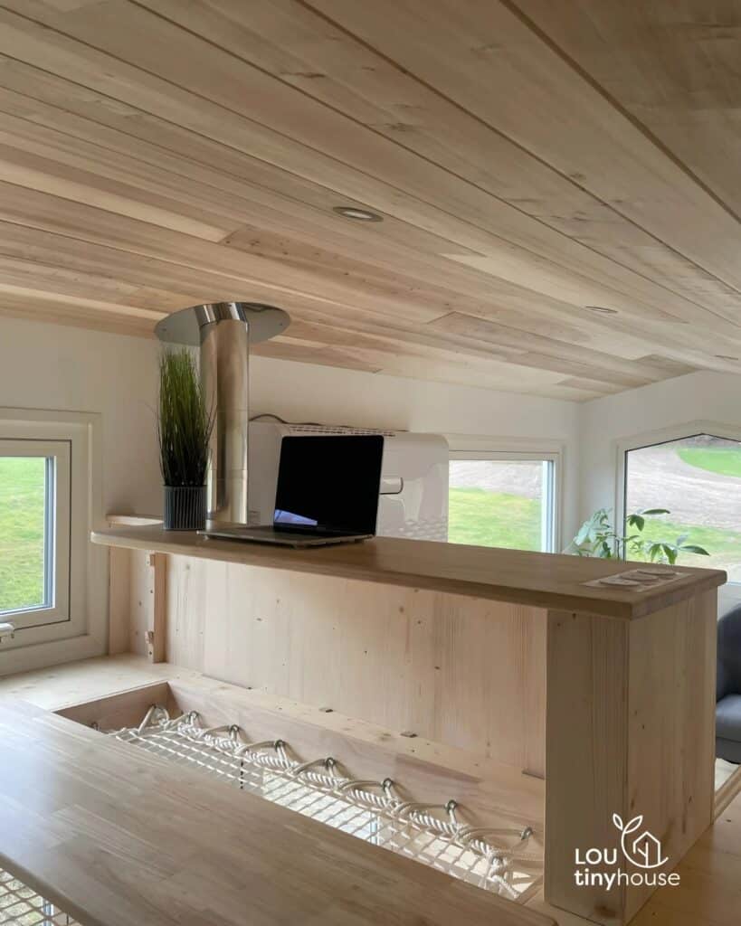 Upper-level workstation with a laptop on a wooden desk and a mezzanine safety net.