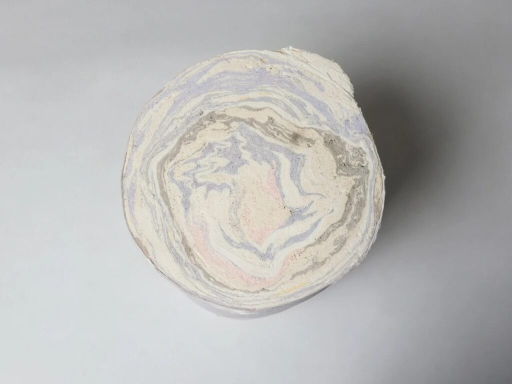 Top-down circular cross-section of a paper log showing concentric rings and marble effect.