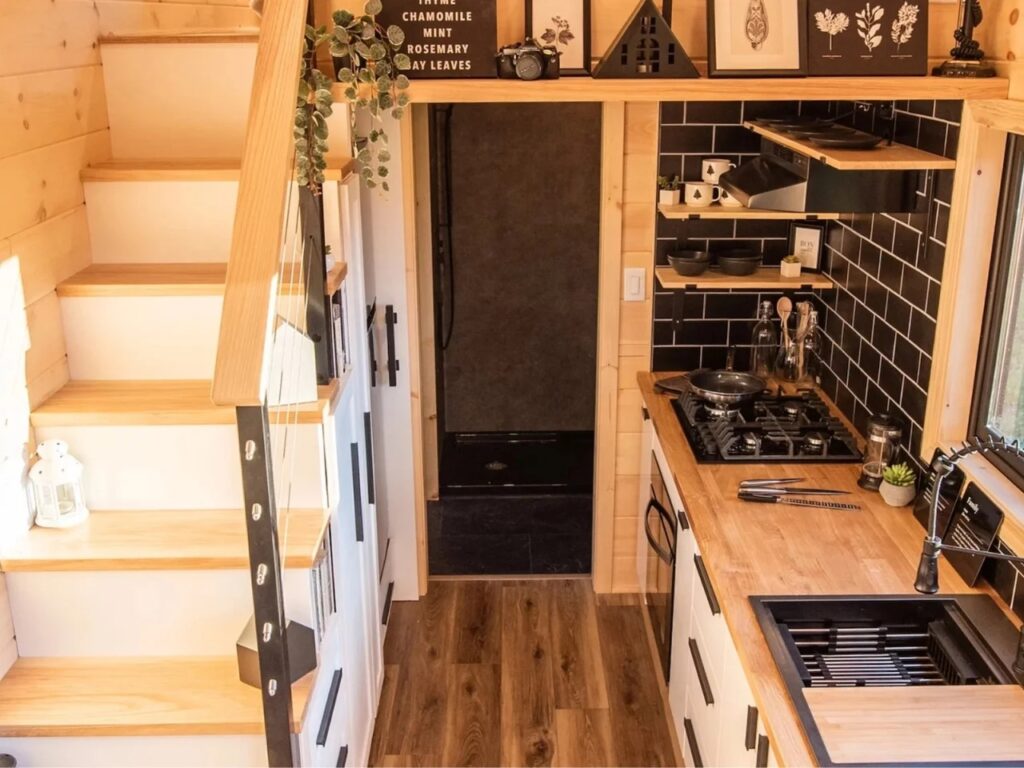 Perspective from the stairs of Scandi Inn showing the integration of the kitchen, storage, and bathroom.