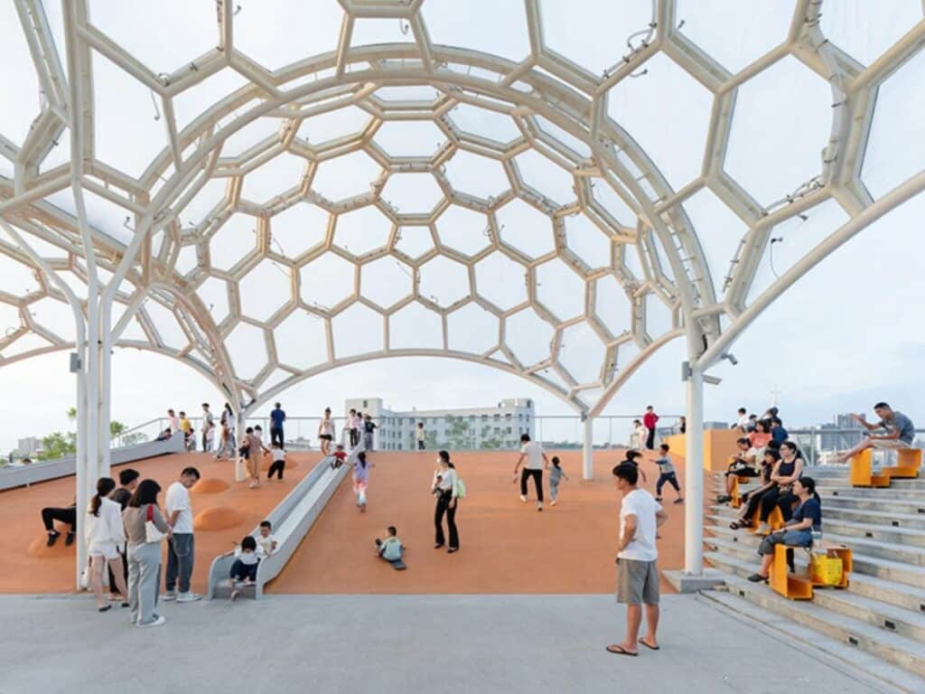 Public gathering and children's slide at the Yongping Warehouse rooftop park under a steel hexagonal structure.