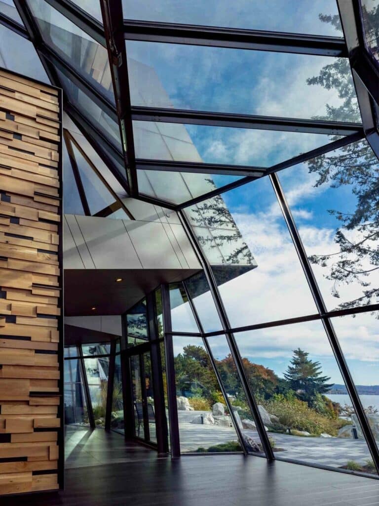 Interior corridor of F-House featuring a wood-slat wall and a dramatic sloped glass ceiling showing the sky.