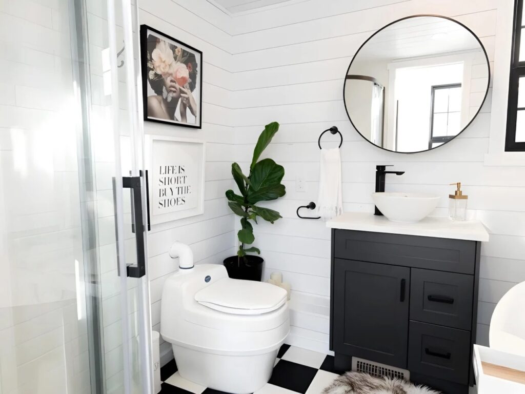 Modern tiny house bathroom with a white vessel sink, black fixtures, and a high-tech composting toilet.