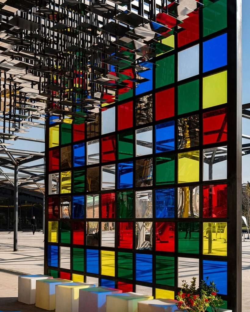Detail of the vertical grid wall composed of colored glass panels and reflective mirror surfaces.