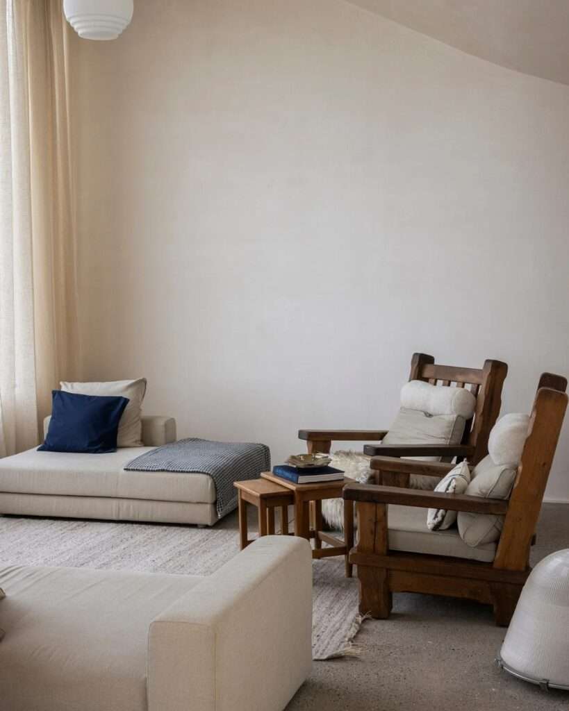 Minimalist living room setup with rustic wooden chairs and neutral upholstery in Villa Nouvelle Vague.