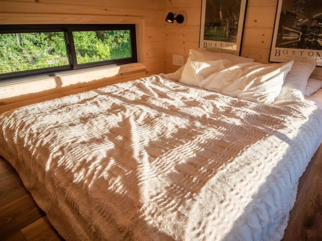 Loft bedroom in Scandi Inn with a large bed, natural wood walls, and boston-themed artwork.