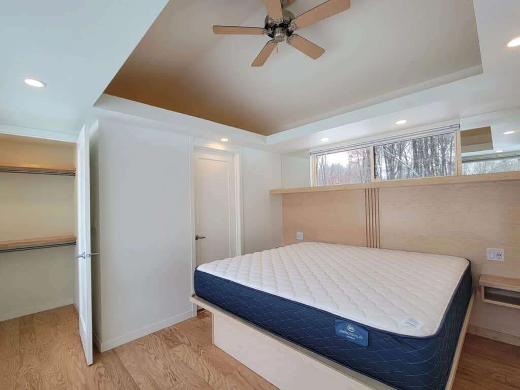 Master bedroom in Shoreline Glass House with a walk-in closet, large bed, and clerestory windows.