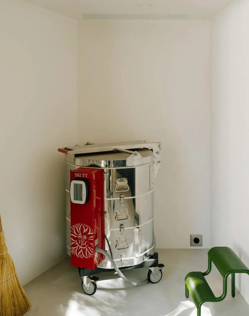 A professional silver and red Skutt ceramic kiln located in the corner of a white-walled studio.