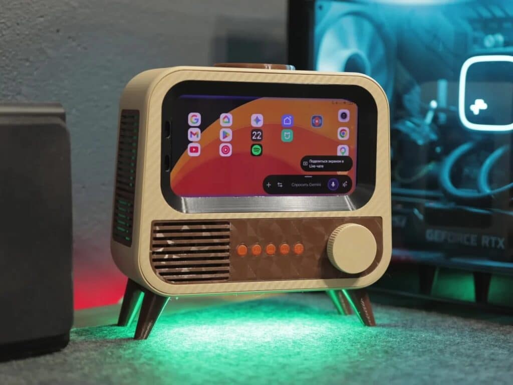 The finished smart speaker with the phone screen showing the Google Gemini interface and smart home icons, glowing with green underlight.