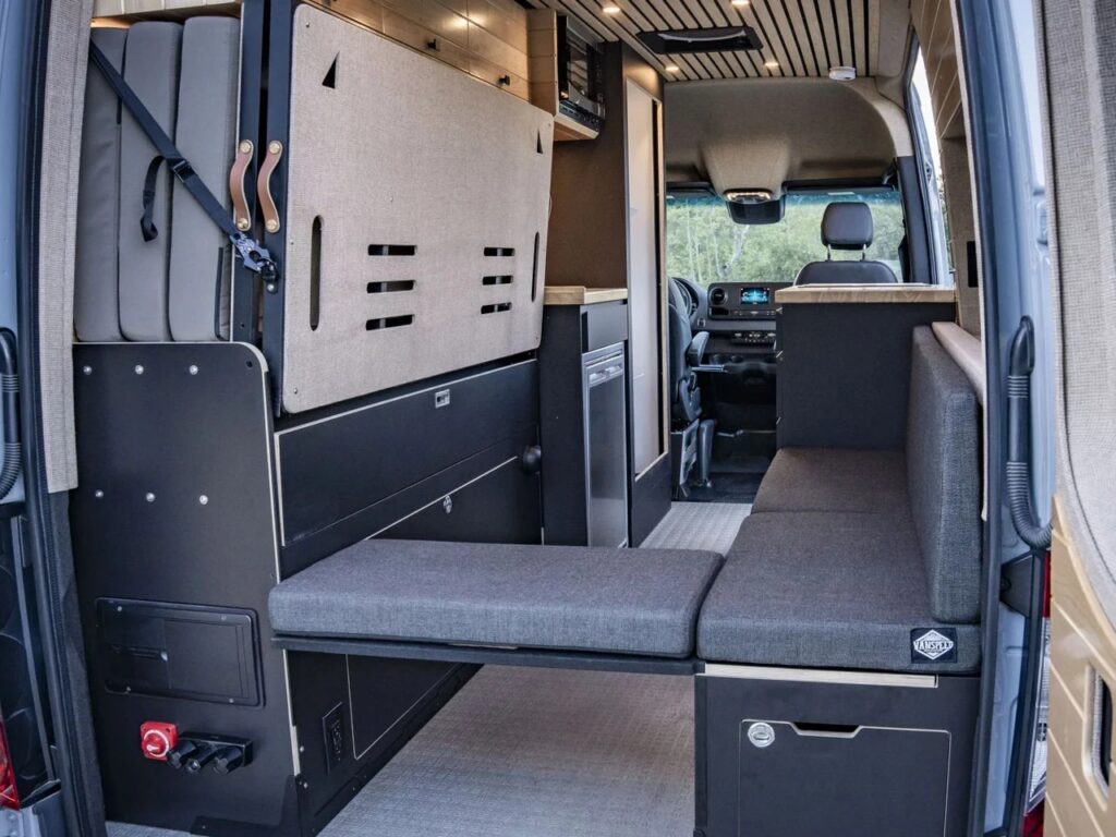 Interior of the Vanspeed Album van showing the multifunctional L-shaped seating and the Murphy bed folded against the driver-side wall.