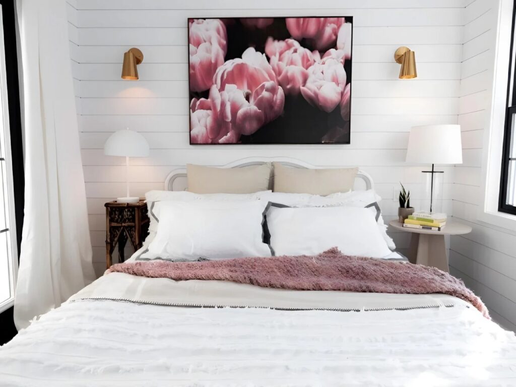 Master bedroom in Daphne tiny house on the ground level with a queen bed and floral wall art.