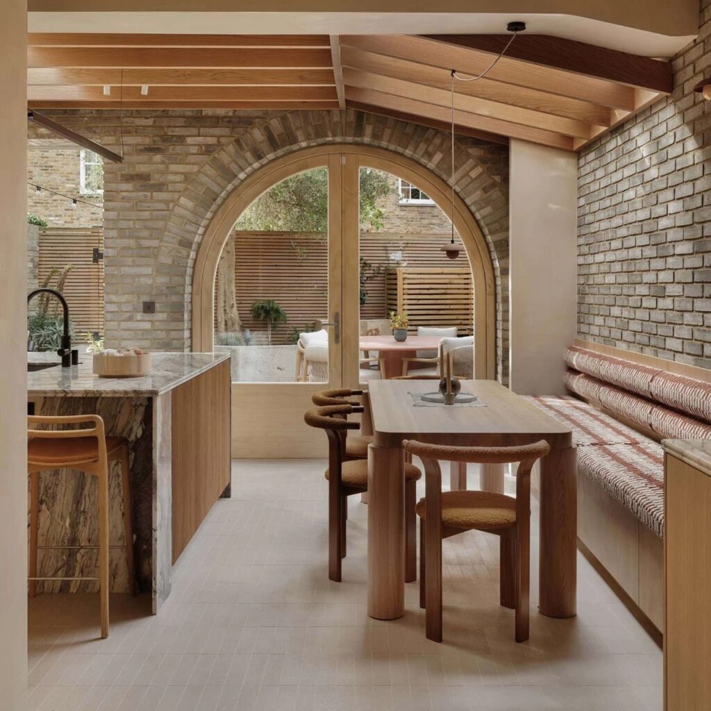Interior view of the dining area framed by a brick arch, featuring a Douglas Fir table and built-in seating.