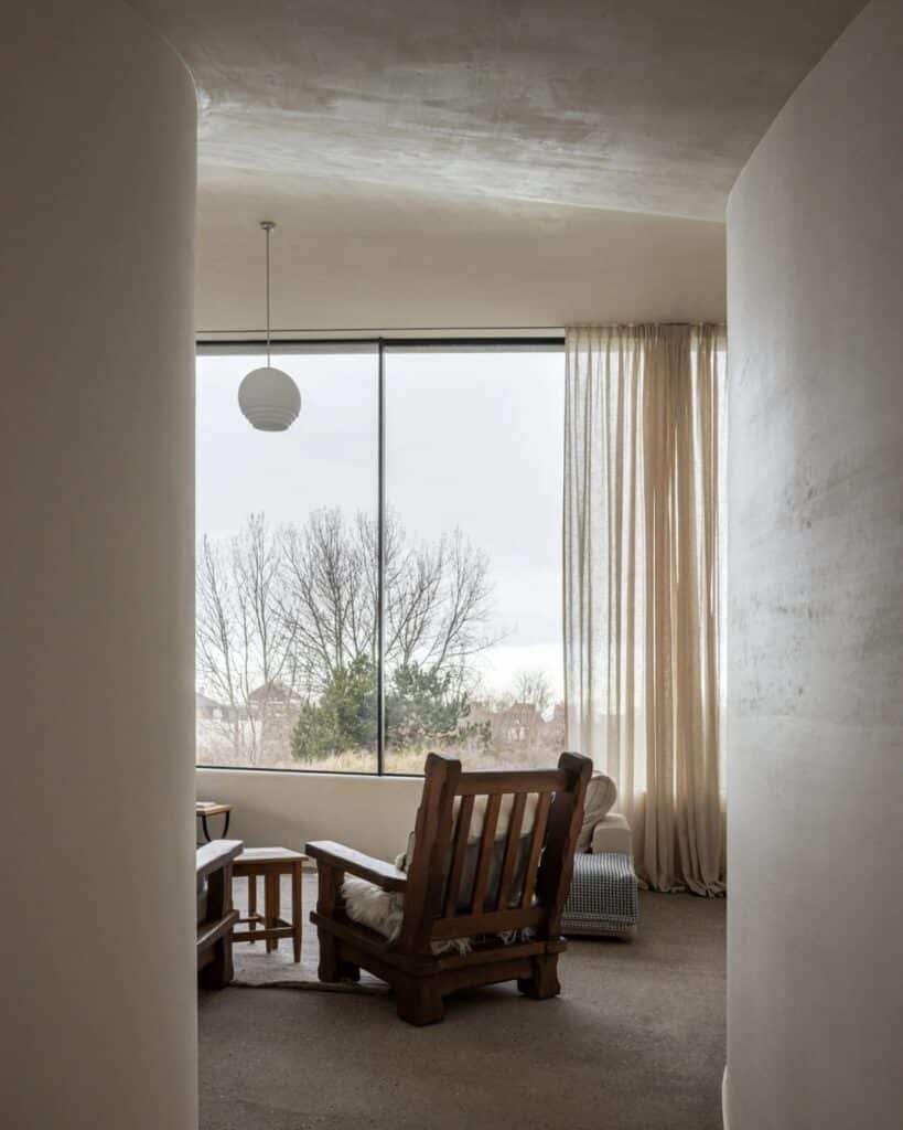 View through a curved white interior hallway toward a large window and the landscape beyond.