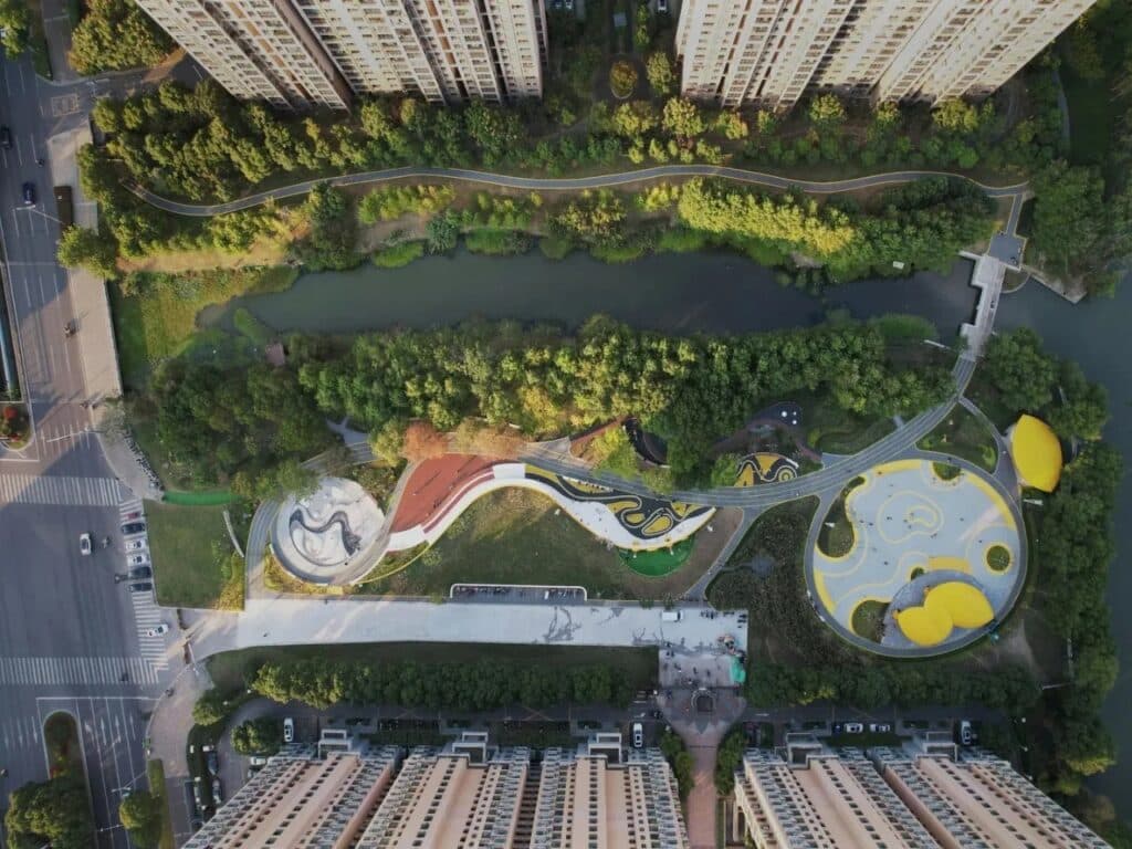 Full bird's-eye view of Orchestra Park in Kunshan showing its elongated shape between a river and high-rise apartments.