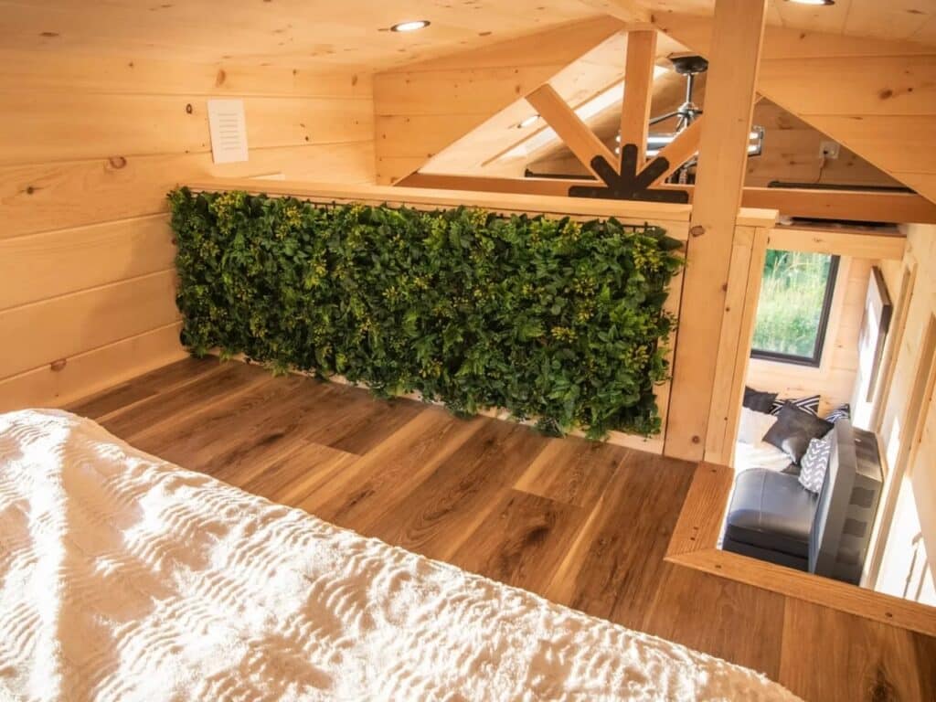 Interior view of the Scandi Inn loft featuring a decorative green plant wall and wooden beams.