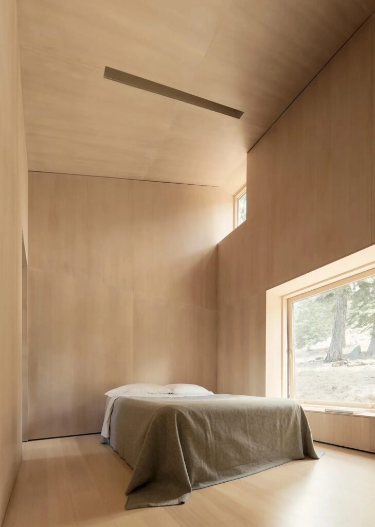 Minimalist bedroom with high ceilings and Douglas Fir plywood walls in Staggered Cabin.