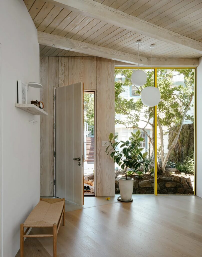 Entrance area of Two-Fold Studio with a view of the garden through floor-to-ceiling glass panels.