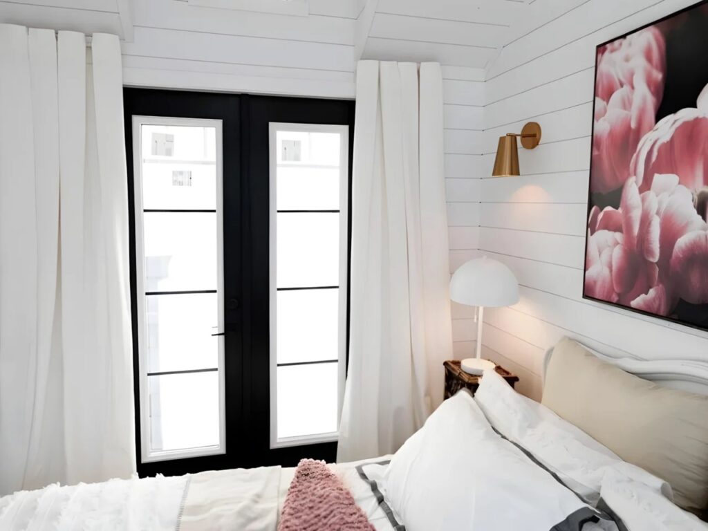 Bedroom view in Daphne tiny house showing double glass doors and abundant natural light.