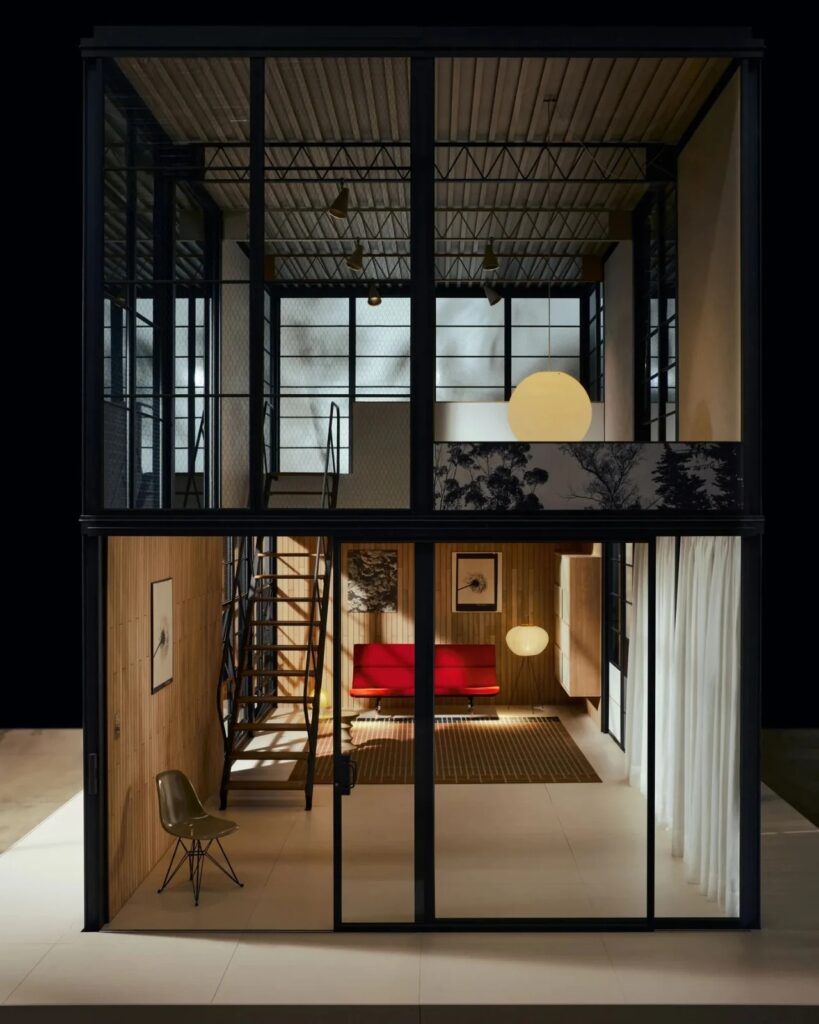 Full frontal interior view of the Eames Pavilion System showing two levels, a staircase, and living area.