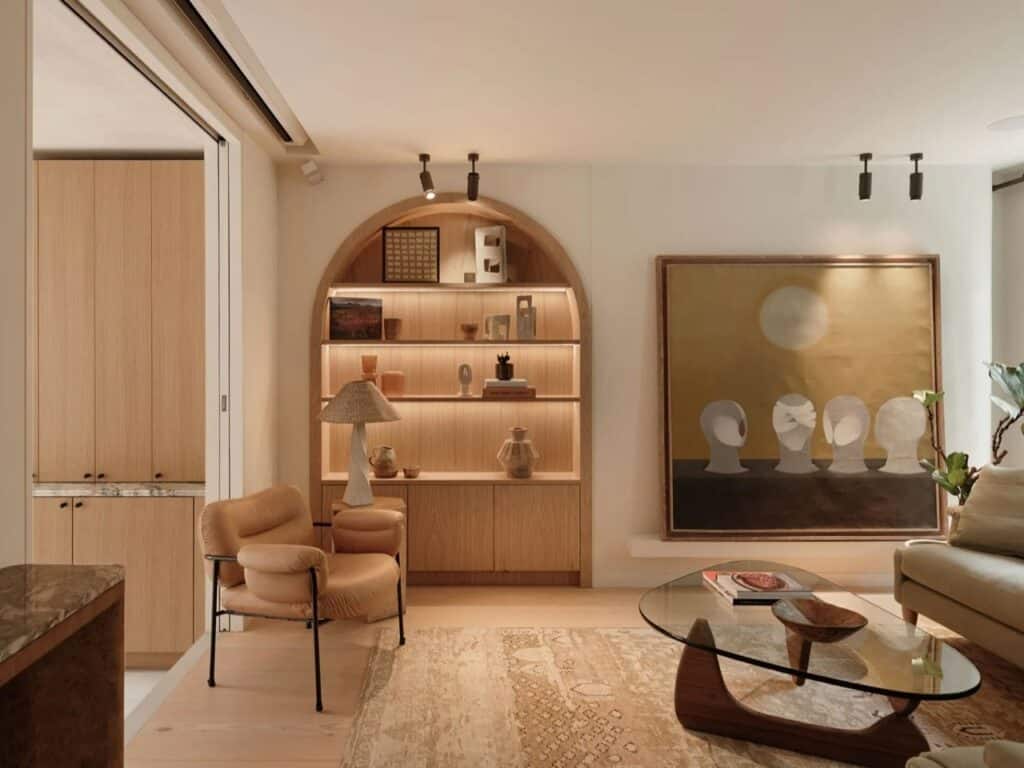 Living room interior with a built-in arched shelving unit made of light wood and warm backlighting.