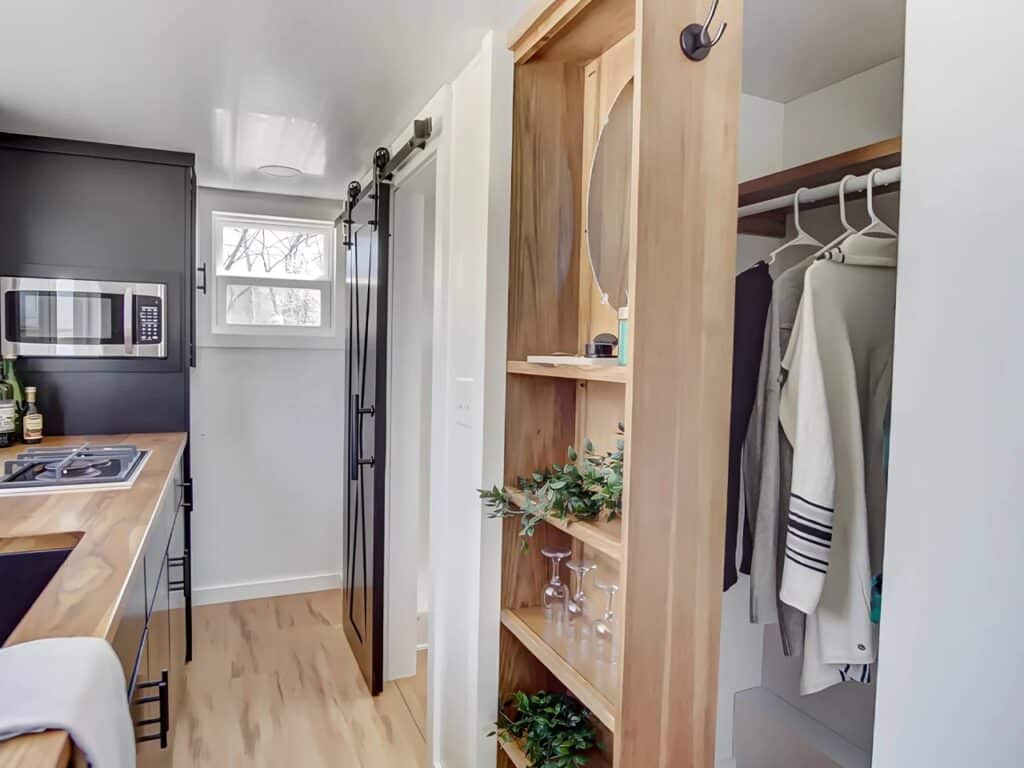 Interior transition showing the open closet and the sliding barn door leading to the bathroom.