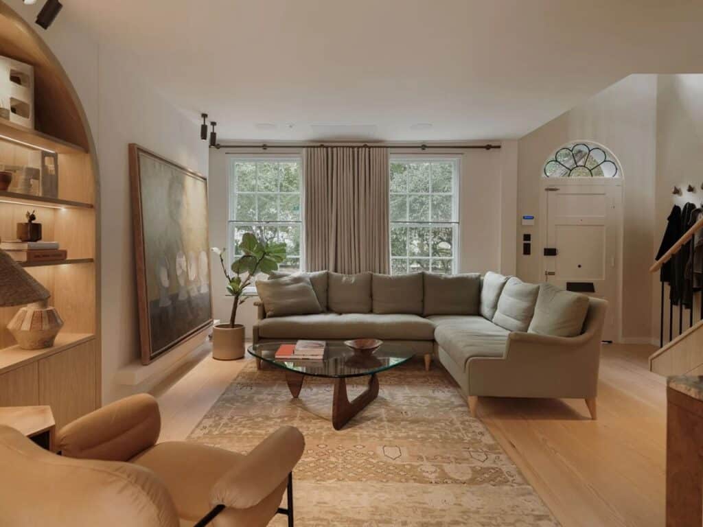 Spacious living room with an L-shaped sofa, glass coffee table, and a view towards the original arched entrance.