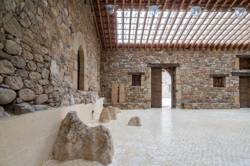 View from inside the pavilion looking towards an open wooden door, showing the continuity of the stone floor.