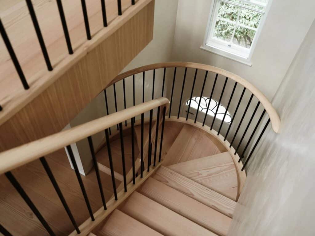 Top-down view of a spiral staircase with Douglas Fir timber treads and slim black metal balusters.