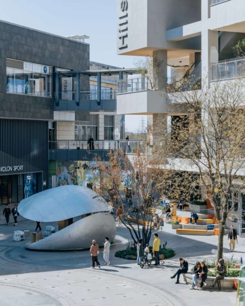 A high-angle view of the Xiangyun town commercial plaza in Beijing with the "Book Shell" pavilion central to the modern commercial buildings.