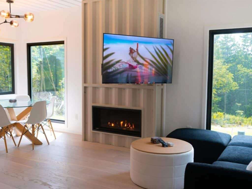 Living room interior of Fairmont Villa with a built-in fireplace inside a container wall section and a modern dining area.