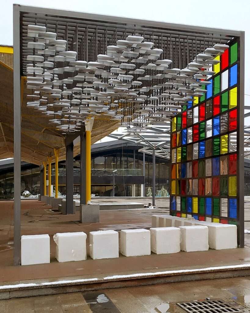 Exterior ground-level view of the Mirror Pavilion under soft daylight, highlighting the reflective ceiling and the industrial surroundings.
