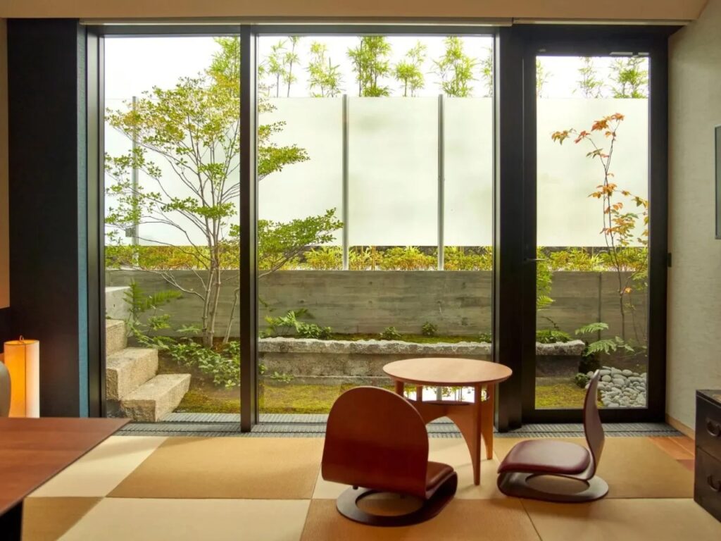 Genji Kyoto guest room with Tatami flooring and a large glass window overlooking a private Tsuboniwa garden.