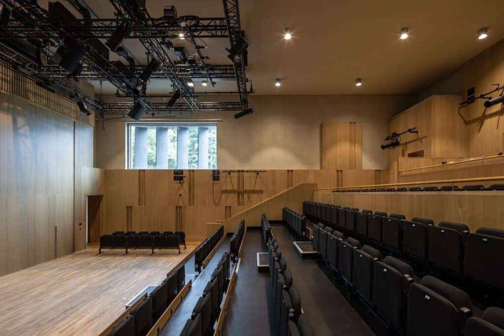 Interior of the multipurpose theater and assembly hall with wood paneling and professional stage lighting.