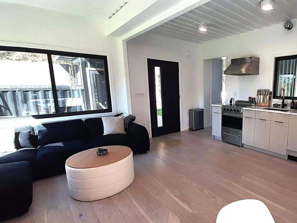 Wide interior view of Fairmont Villa’s living room and kitchen area showing the open floor plan and large windows.