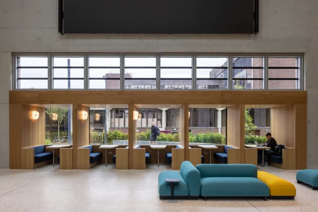 Contemporary student lounge featuring private wooden study booths and colorful modular seating.