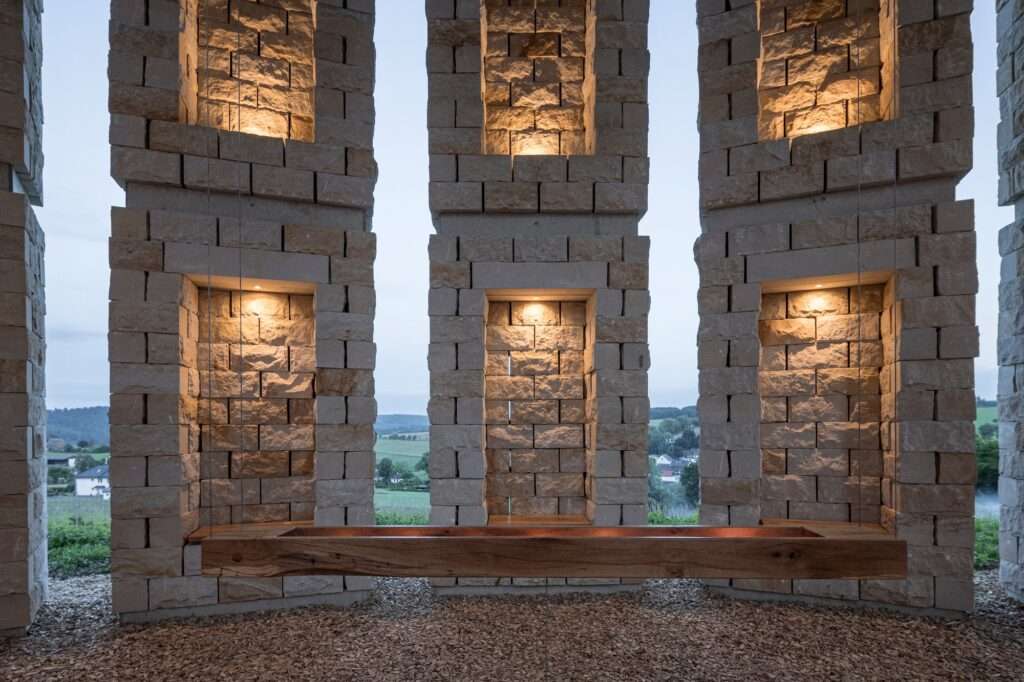 Symmetric view of lighted niches in the sandstone walls of the Open Chapel overlooking the misty valley.