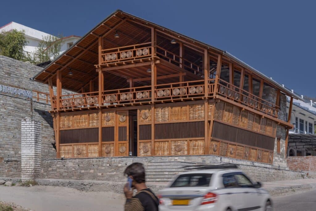 Low-angle perspective of the building's corner, highlighting the stone plinth and the multi-layered wooden balconies.