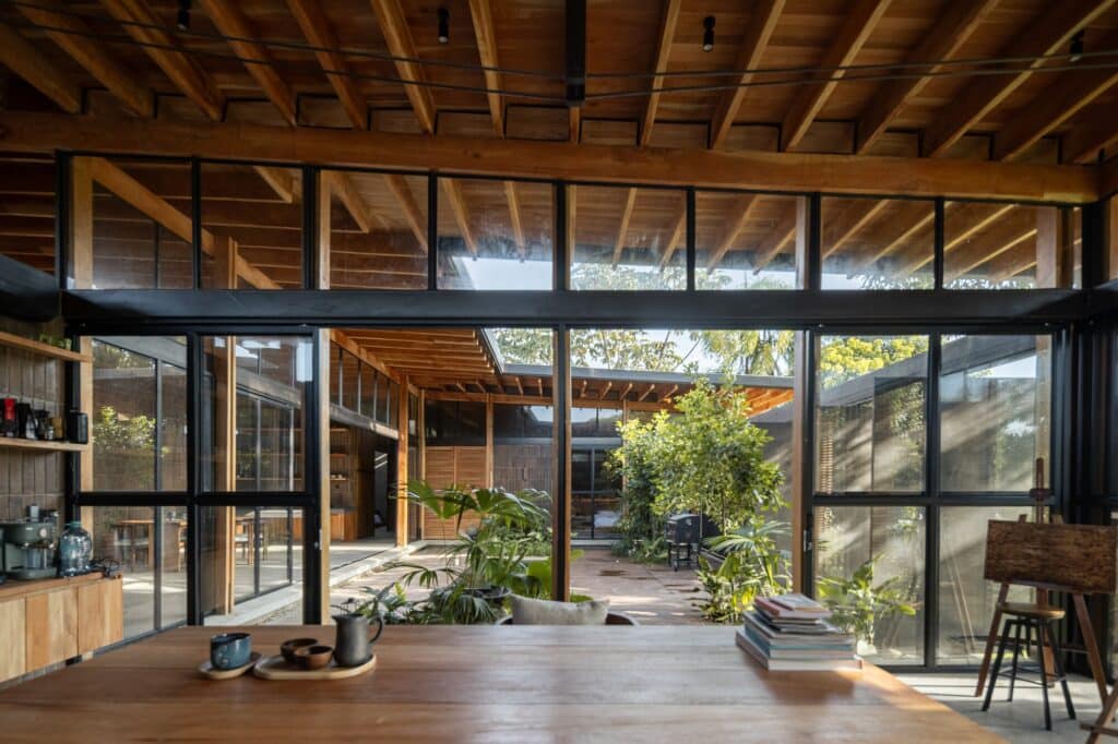 View from the creative studio looking through large glass doors into the internal garden and wooden structural beams.