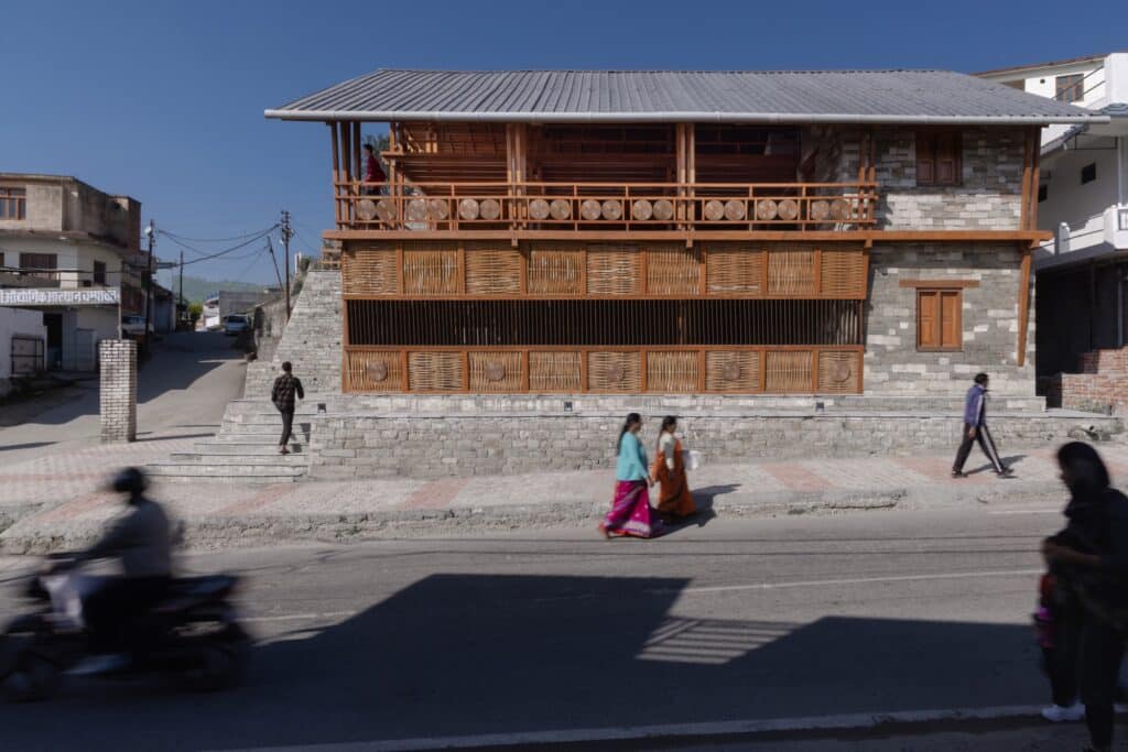 Wide shot of the Champawat Market Plaza with local people walking in front, showing the scale of the building.